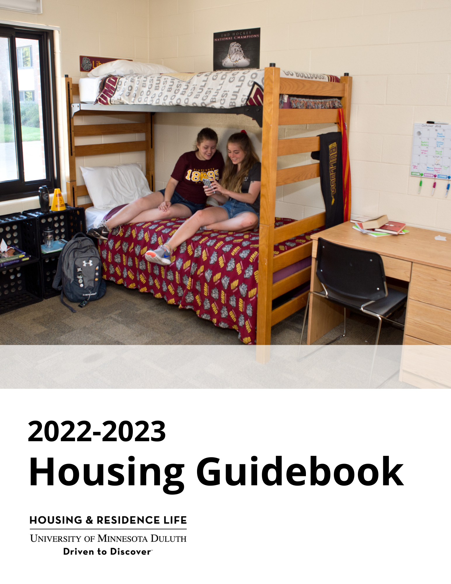 cover of UMD 2022-2023 Housing Guidebook, image shows two students in UMD shirts sitting on a lofted bed looking at a phone